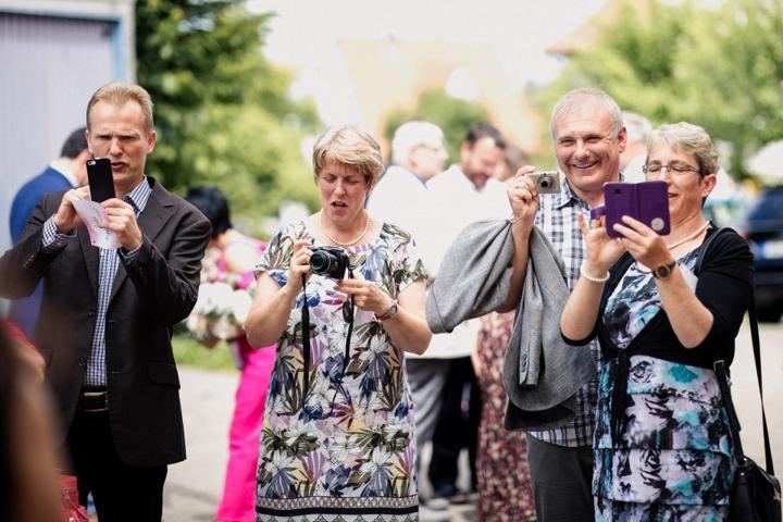 Hochzeitsgäste fotografieren und filmen den besonderen Moment mit Kameras und Handys.